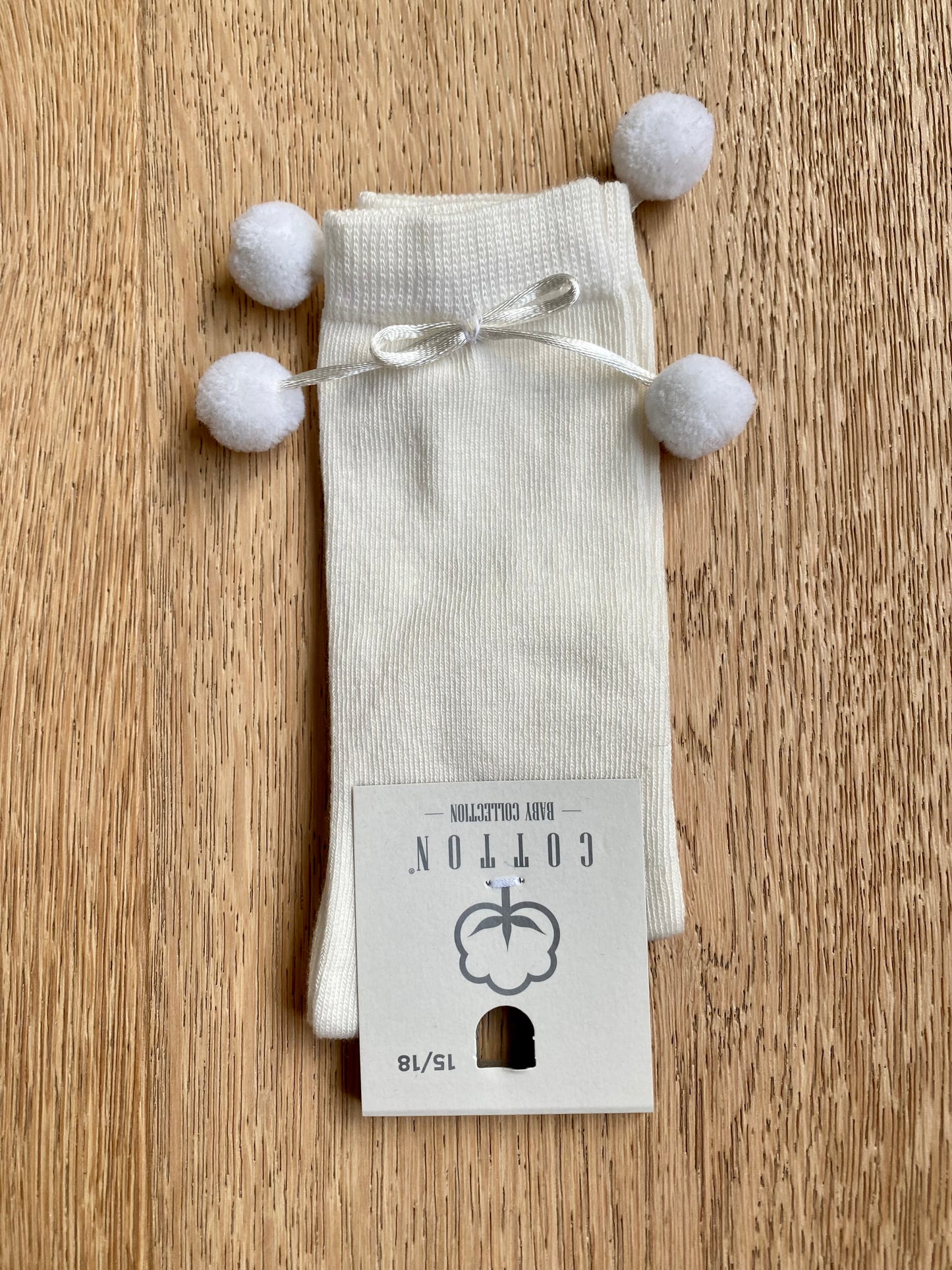 Gebroken witte kniekous met pomponnetjes