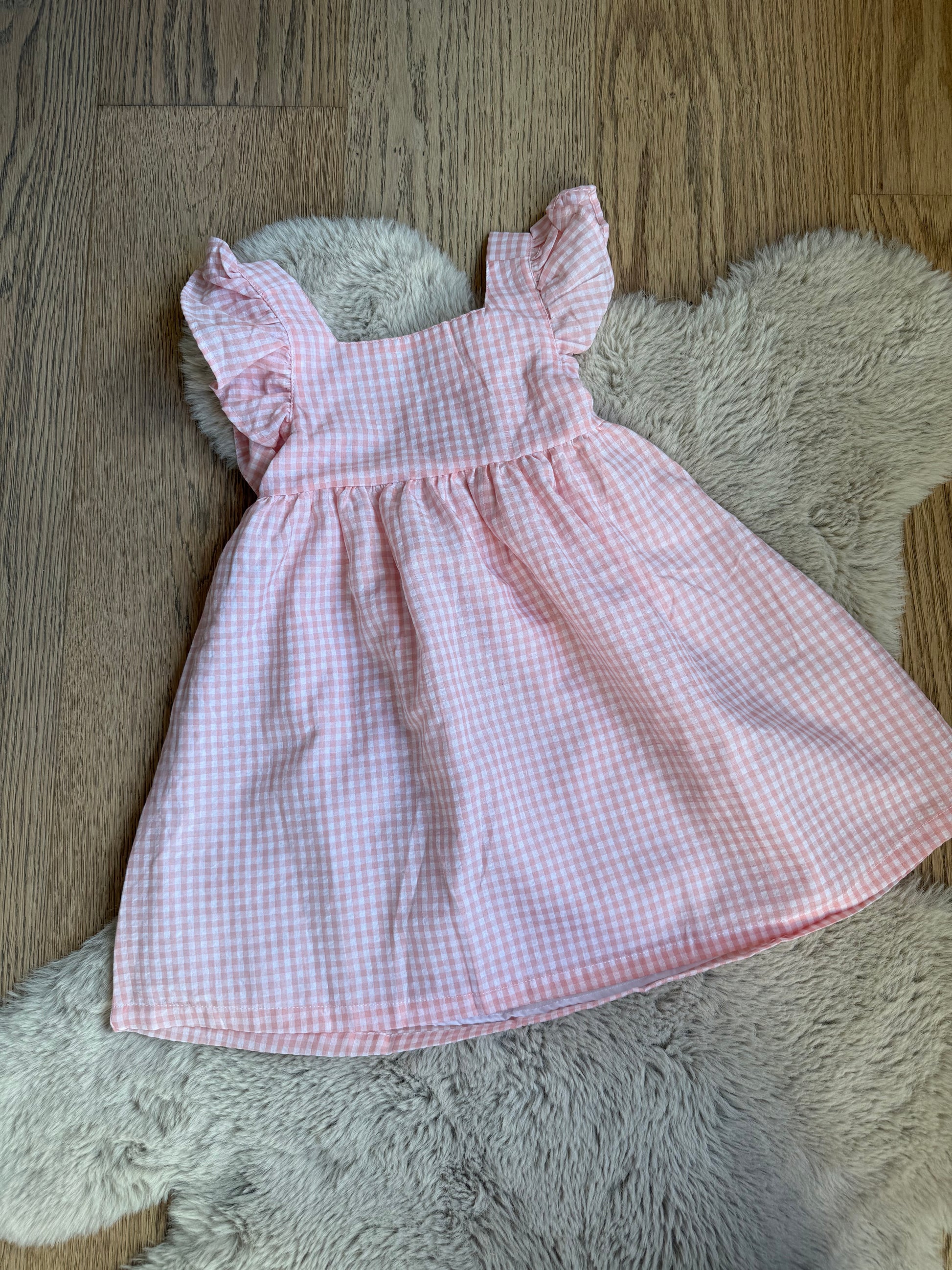 Roze feestjurk voor meisjes van Newness Kids met centrale strik en zachte plooien.