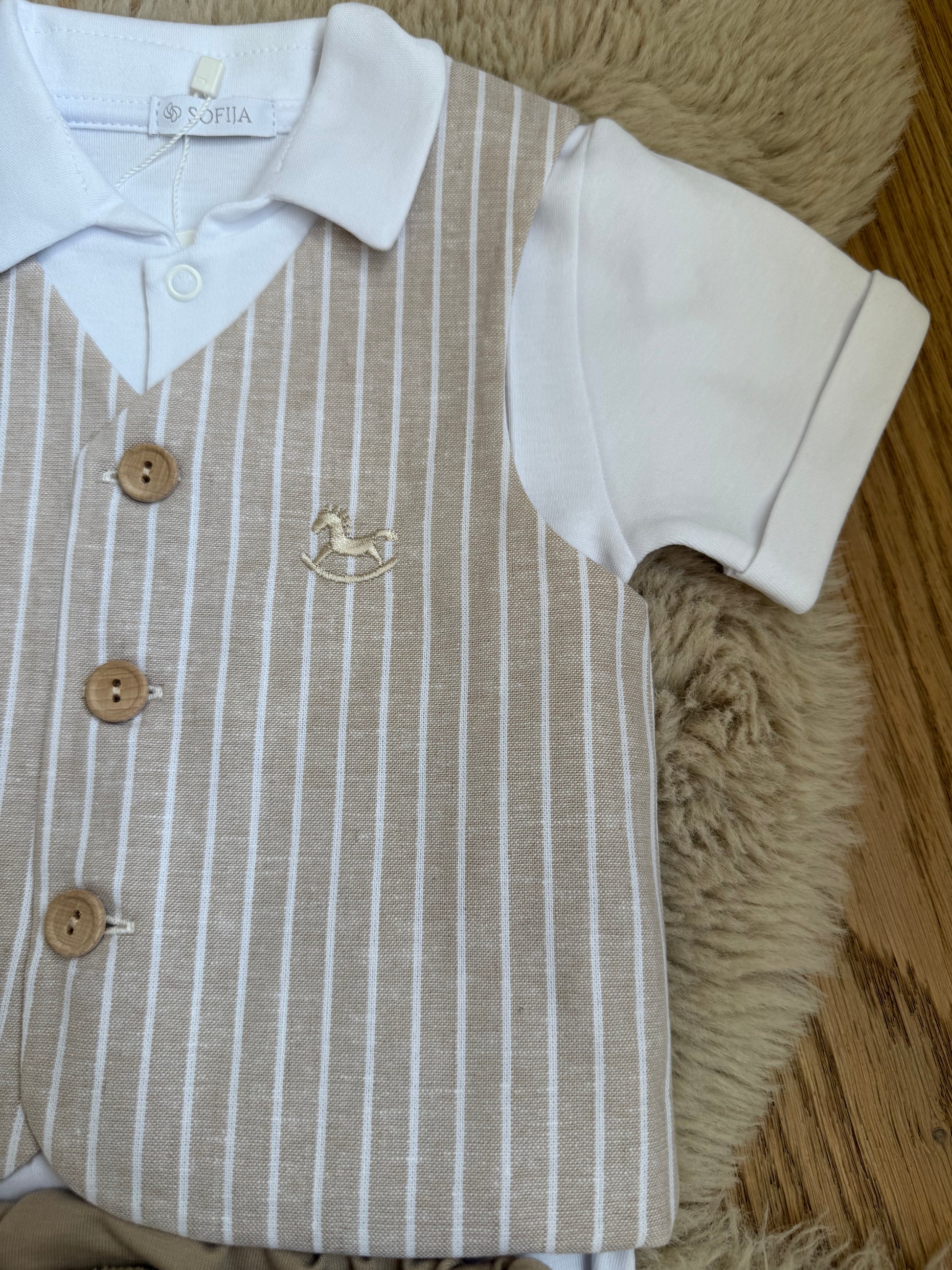 Detail van beige babykostuum jasje met subtiel hobbelpaard accent